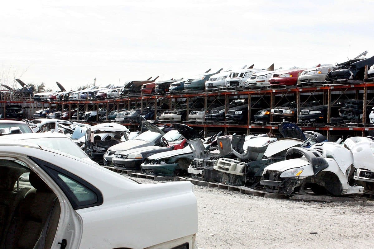 Discount Auto Salvage: Rows of wrecked cars stacked on tall metal racks in a salvage yard, with damaged vehicles in the foreground