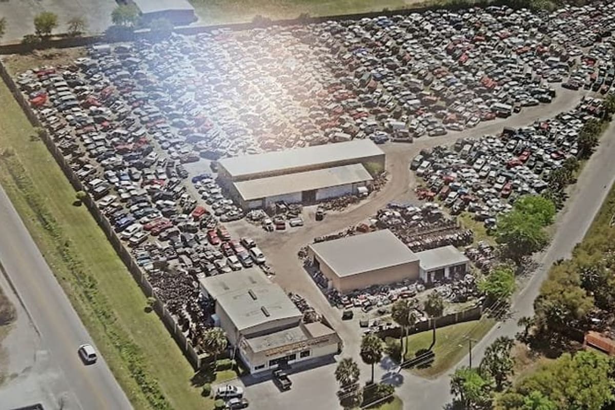 Sanford Auto Salvage: Aerial view of a large salvage yard with rows of vehicles, warehouse buildings and a front office along a road