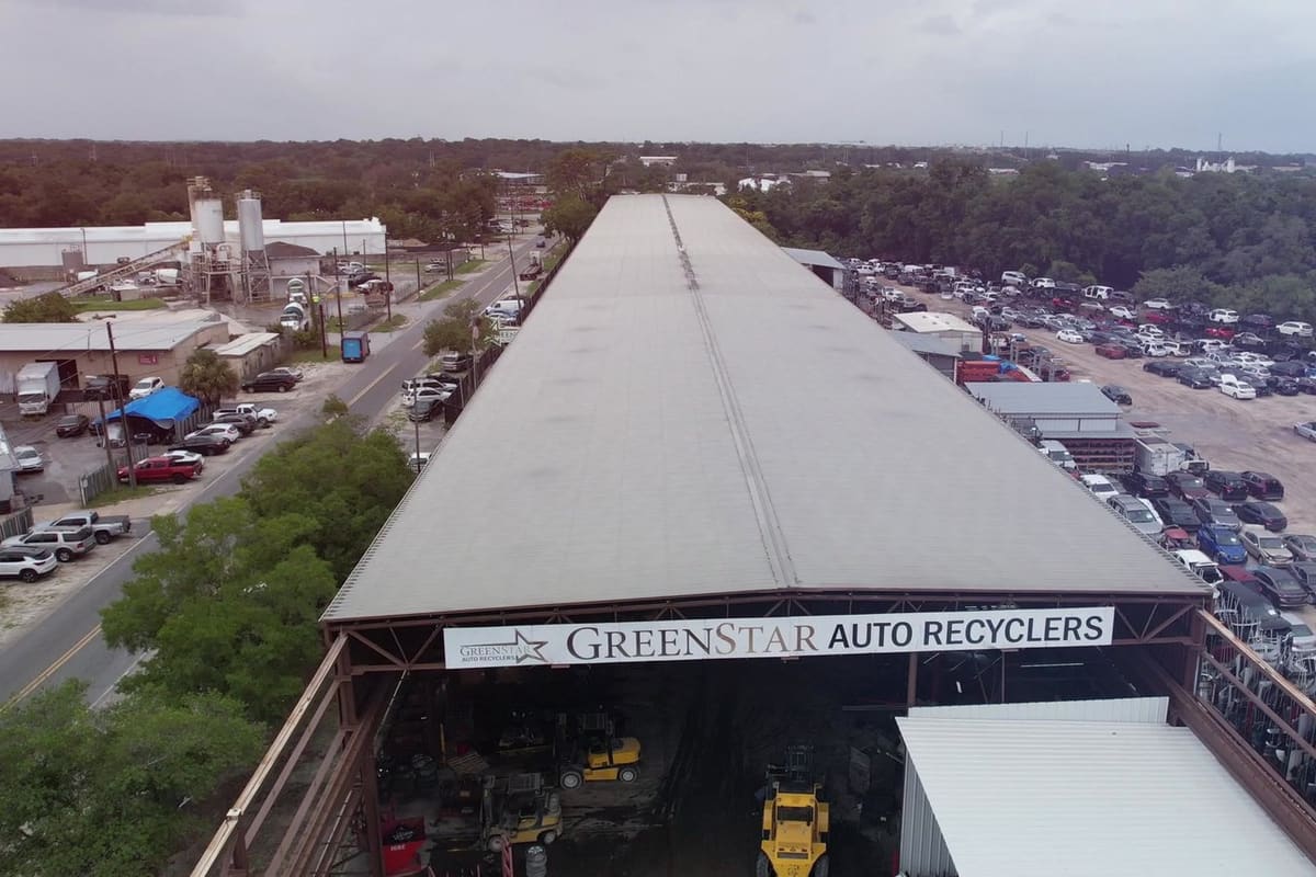 Green Star Auto Recycling: Aerial view of a large covered salvage building beside a lot filled with rows of cars and a road with trees