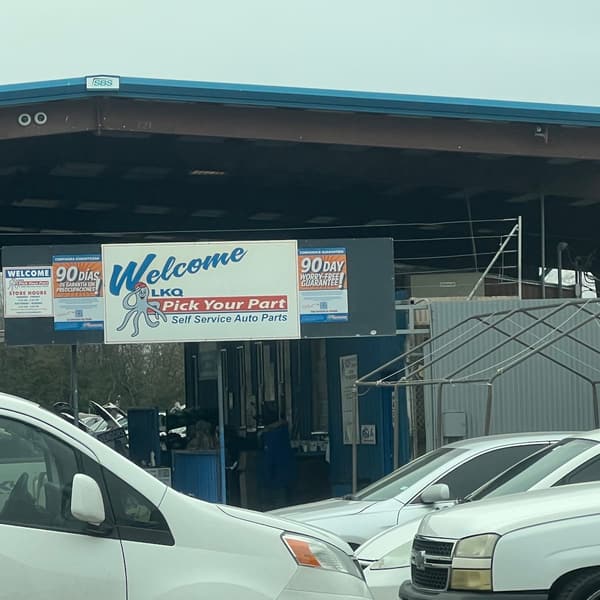 Pick Your Part - Houston Northville: Covered entrance to a self-service auto parts yard with a welcome sign, admission sign and cars parked in front