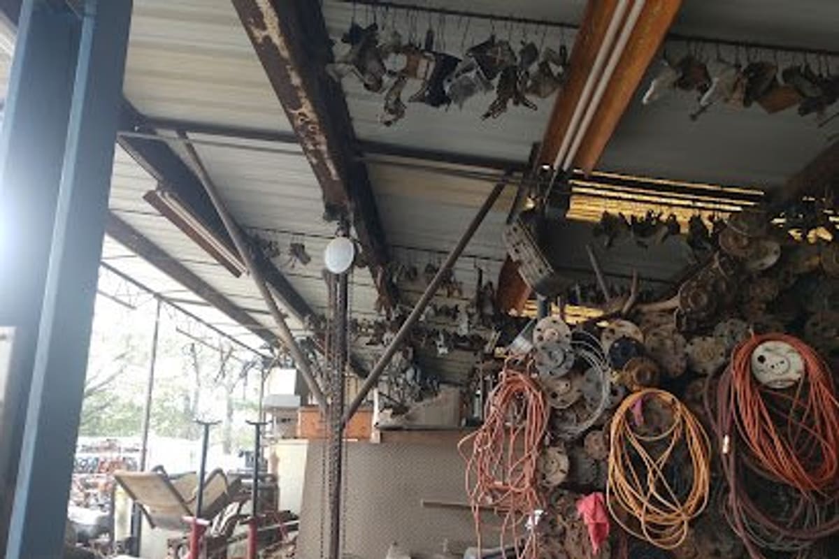 Pasadena 4X4 Salvage & Repair: Covered salvage area with auto parts, wheel hubs and extension cords hanging under a metal roof