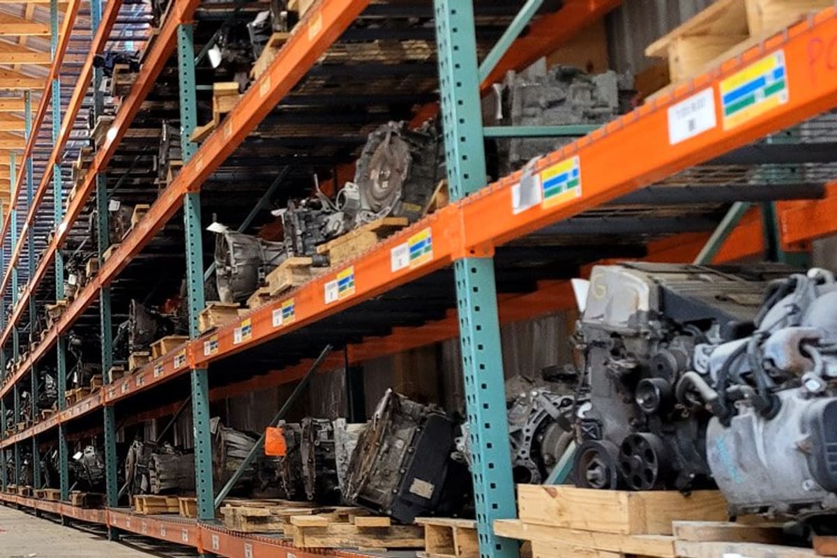 Raceway Auto & Truck Parts: Long warehouse aisle with tall steel racks holding rows of used engines and auto parts on pallets