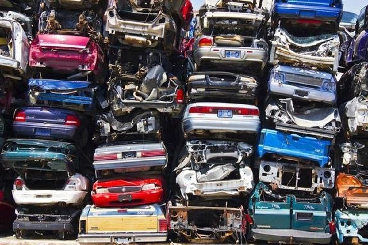 ABC Junkyard: Tall stacks of crushed cars piled several high in a salvage yard on a sunny day