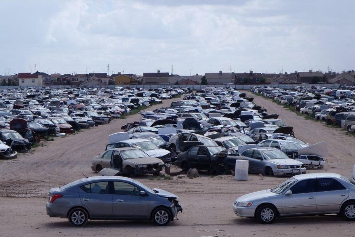 LKQ - El Paso: Wide daytime view of a large salvage yard with rows of wrecked cars on dirt lots and houses in the distance