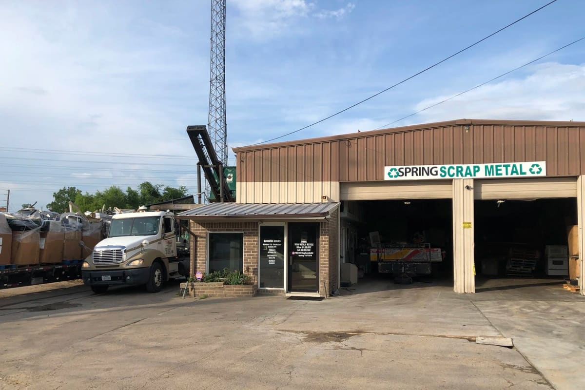 Spring Scrap Metal Recycling: Metal warehouse with open bays, small brick office, and semi truck beside stacked scrap bales