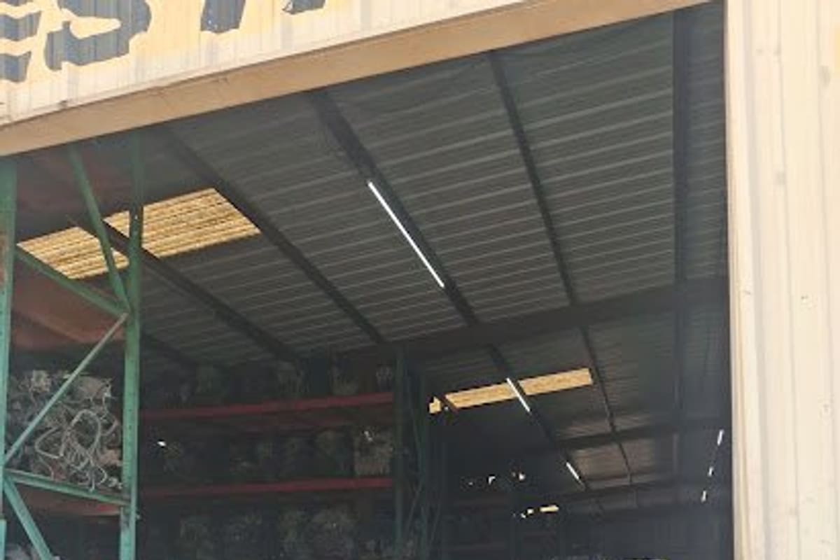 J & B Auto Parts: Open warehouse bay with tall shelving racks full of used auto parts and a truck bed in the foreground