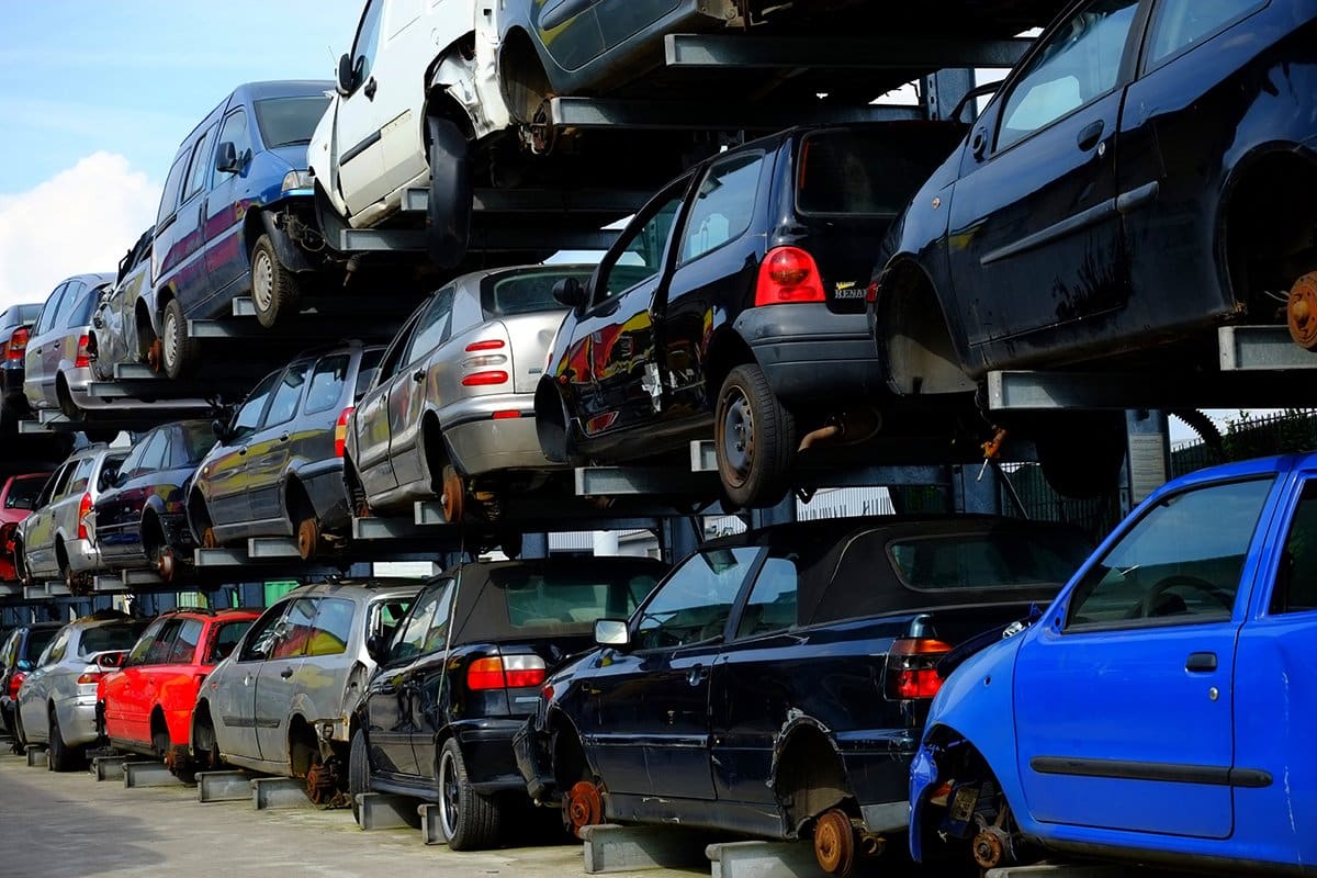 Auto Parts Pros: Rows of wrecked cars stacked on tall metal racks in a salvage yard under a blue sky