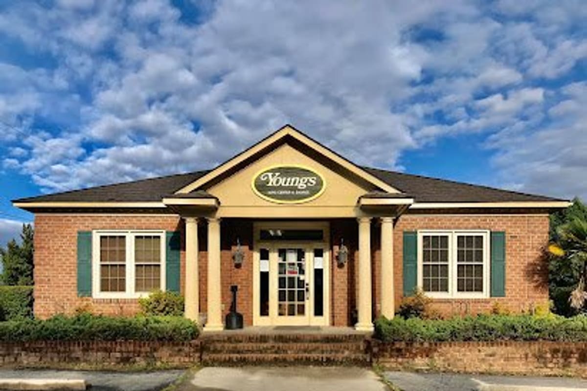 Young's Auto Center & Salvage: Brick office building with columned front entrance and oval sign under a blue sky with clouds