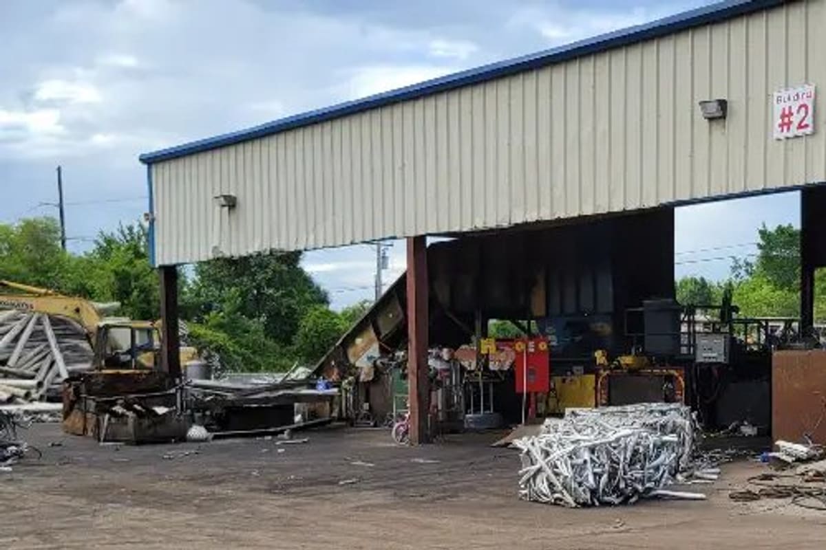 Wright's Scrap and Recycling: Open-sided metal shed building at a scrap yard with a bale of aluminum scrap and equipment on a dirt lot