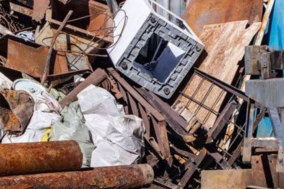 MR. Scrap: Piles of rusty scrap metal, pipes and appliances on the dirt ground of a salvage yard