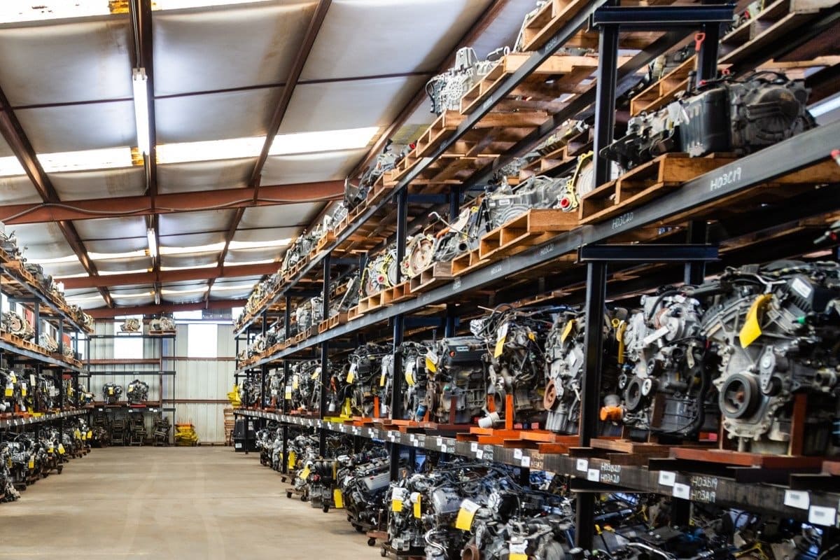 Counselman Automotive Recycling: Warehouse aisle lined with tall racks holding rows of used engines on pallets and carts