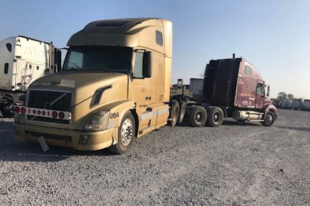 Alamo Truck Sales & Used Parts: Gravel lot with semi trucks parked, a tan tractor cab in front and other trucks in the background