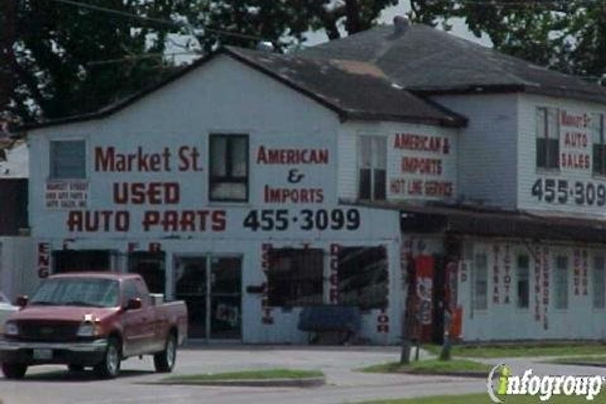 Market St Used Auto Parts & Auto Sales: White two-story building with painted signs for used auto parts and auto sales, a red pickup parked in front