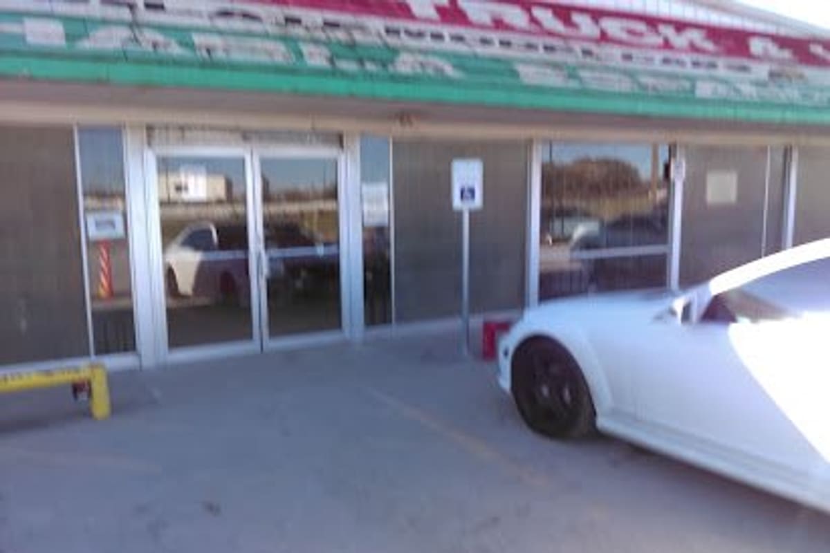 Mid Cities Jeep Truck & Van: Storefront with glass double doors, a green and red sign band above, and a white car parked in front