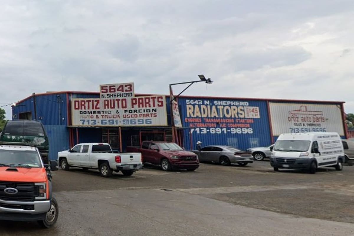 Ortiz Auto Parts 2: Blue auto parts building with signs and rooftop address, with trucks and cars parked in the lot out front