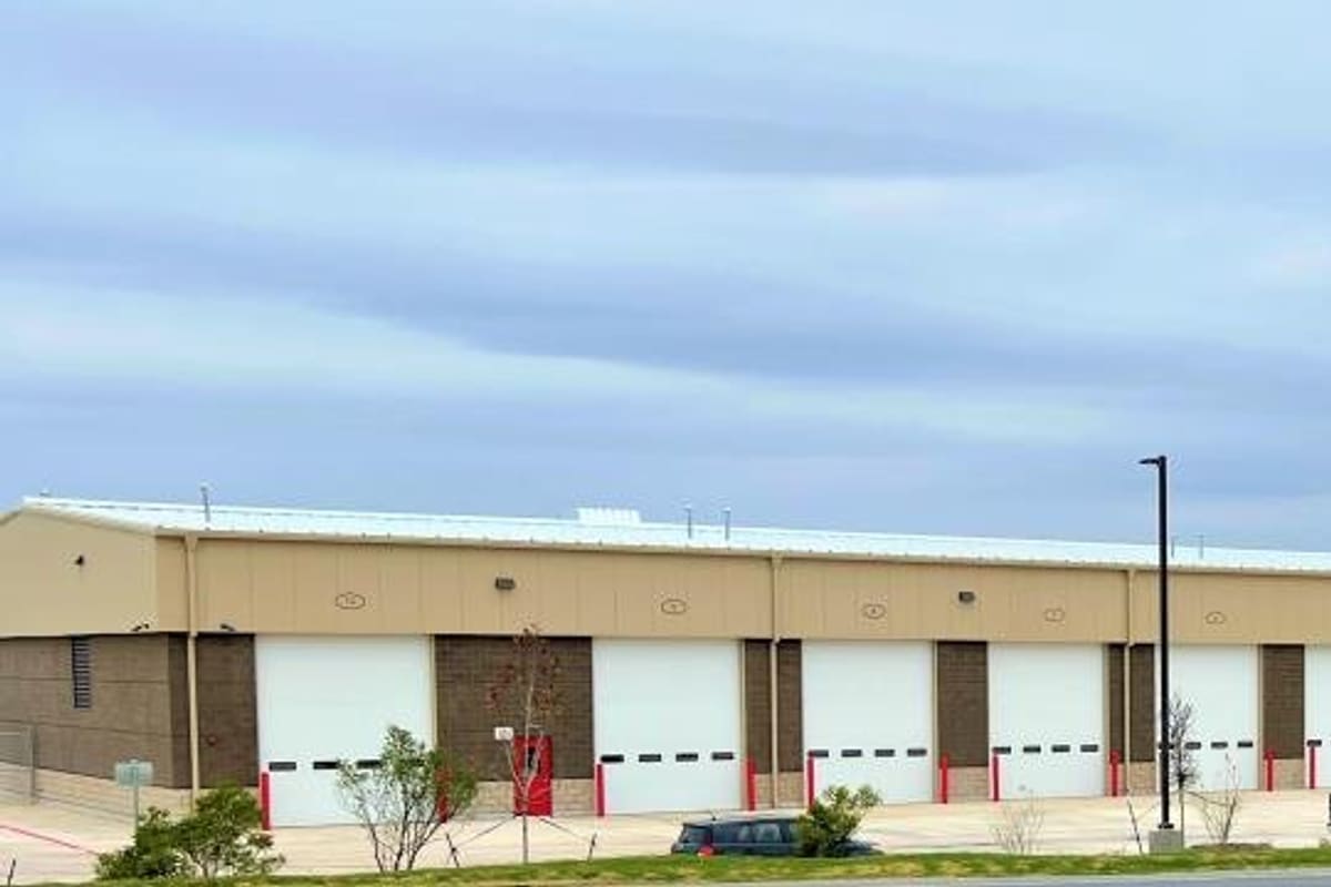 Inland Truck Parts & Service: Long tan and brown commercial building with a row of white overhead bay doors and parked vehicles in front
