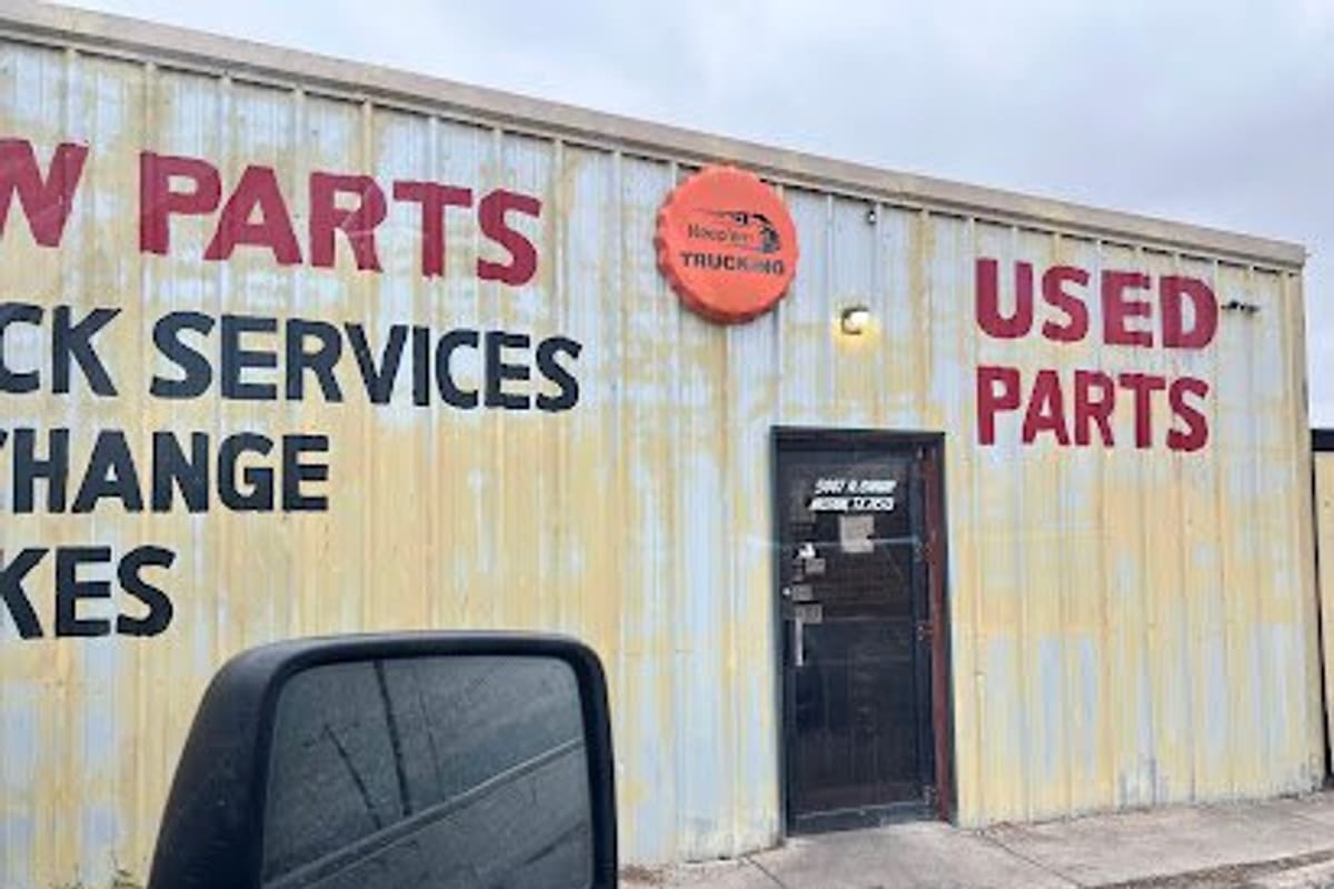 Joes Junk Yard: Weathered metal building with painted signs reading used parts and truck services, and a dark entrance door