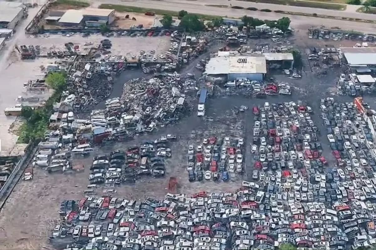 U-Pull and Save: Aerial view of a large salvage yard with dense rows of cars, a central building, and trees along one side