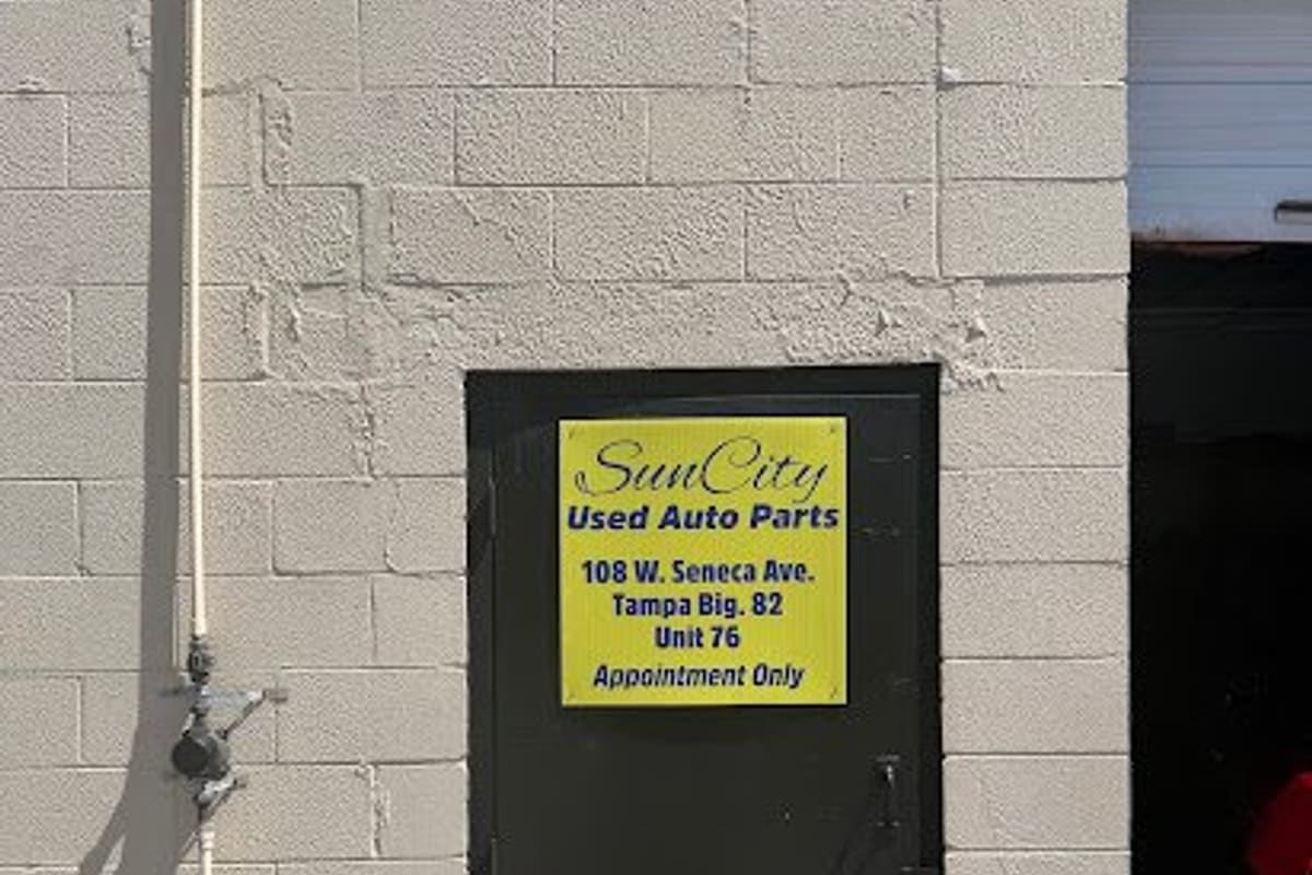 Sun City Used Auto Parts: Black steel door with a yellow sign for used auto parts, unit 76, on a painted cinder block wall