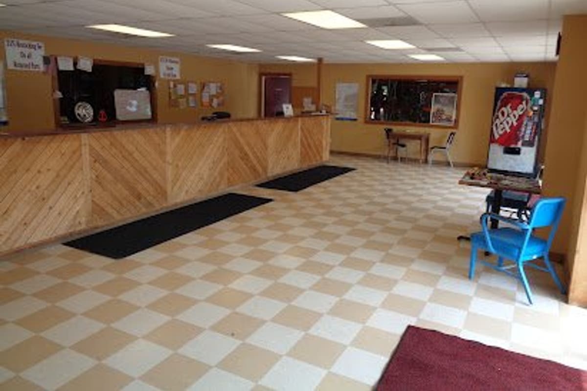 JM Salvage: Inside the front office with a long wooden service counter, checkered tile floor, vending machine and a blue chair