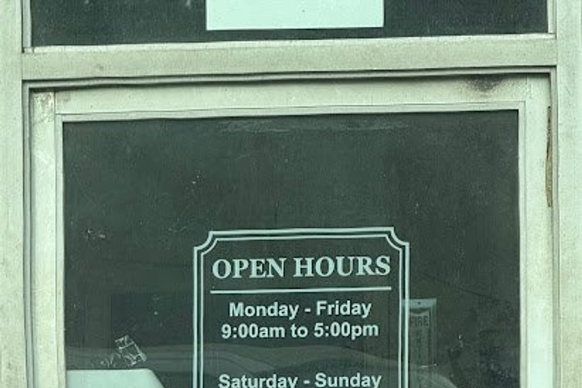 Goodnews Auto Sales & Salvage: Glass entry door with a posted open hours notice and a handwritten sign taped to the window