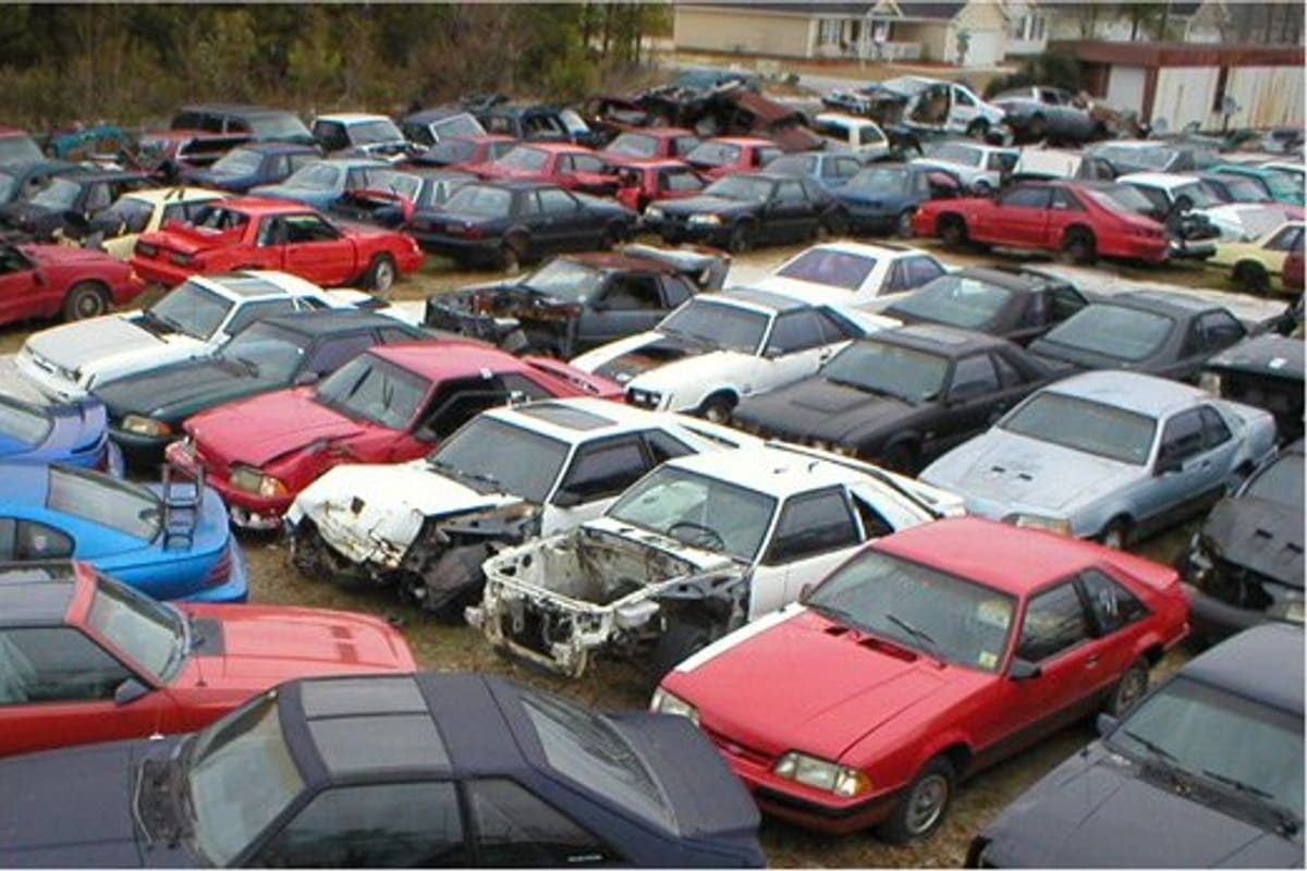 Gagel's Auto Parts: Rows of salvage cars parked closely together in an outdoor yard, with trees and houses in the background