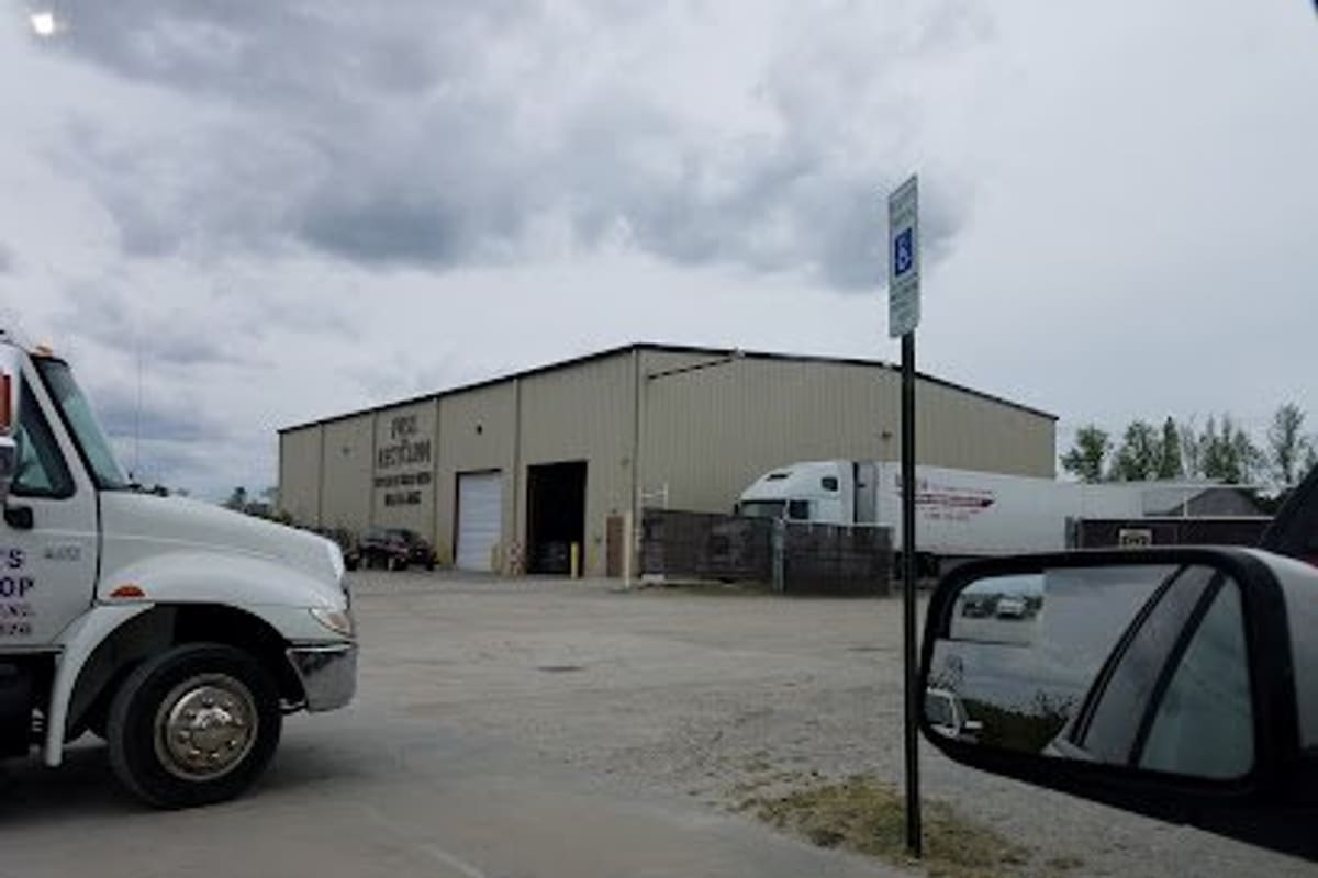 Foss Recycling - La Grange Facility: Large tan metal warehouse building with a bay door, a white tow truck in the foreground and a semi trailer parked beside it