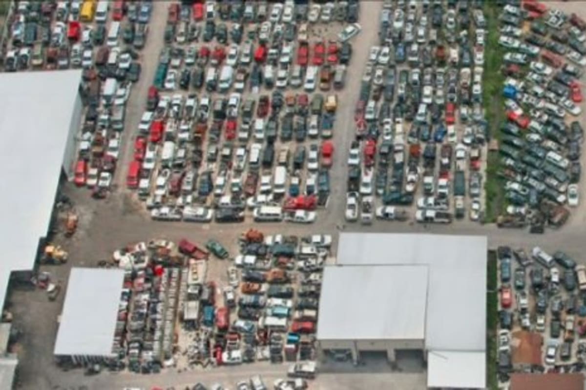 A Plus Auto Parts: Aerial view of a salvage yard with rows of parked vehicles and several warehouse buildings