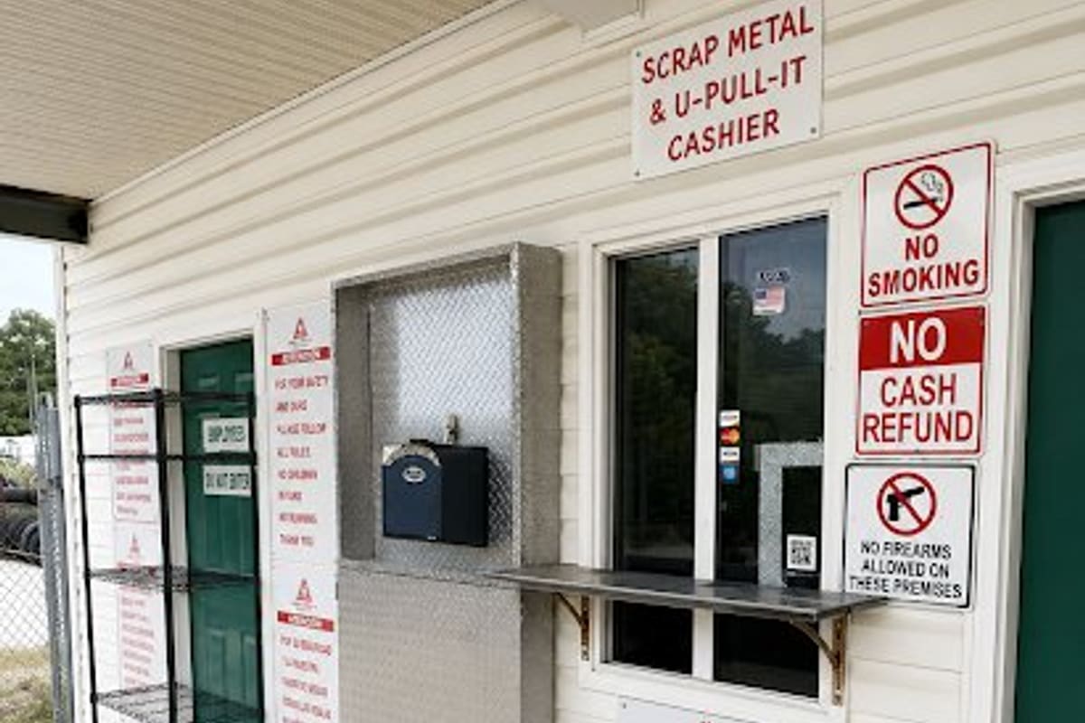 Foss U-Pull-It Havelock: Cashier window and signs on the outside of a cream-sided office building with green doors under a covered porch