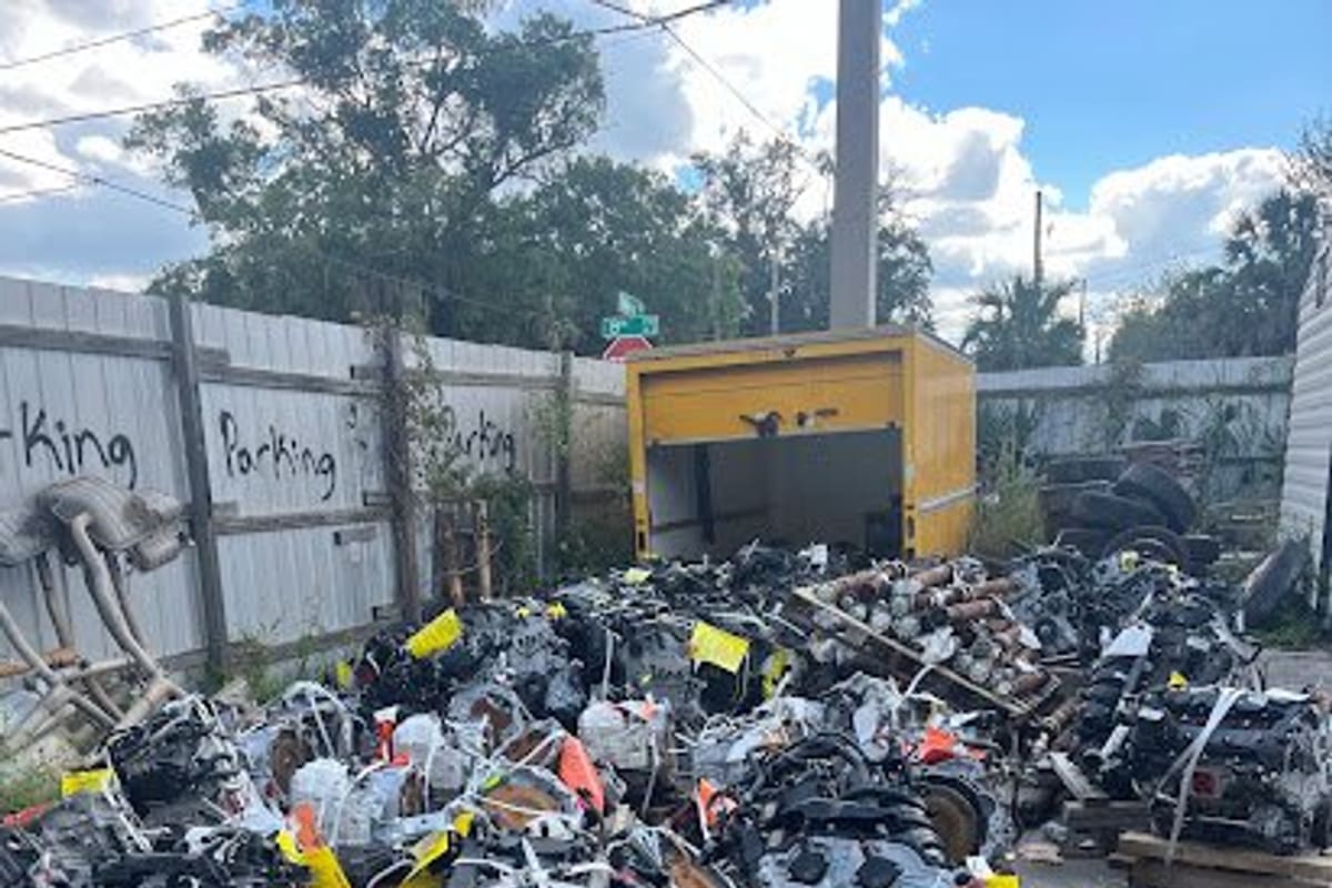 Abs Auto Salvage: Rows of used engines on wooden pallets with yellow tags in an outdoor salvage yard beside a wooden fence