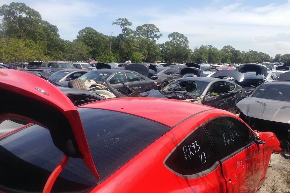 M&K Used Auto Parts: Rows of wrecked and salvaged cars packed across an outdoor lot under a blue sky with trees behind