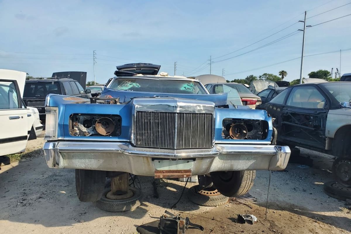 Pick Your Part - Largo: Rows of wrecked cars sitting on bare ground in a salvage yard under a blue sky with power lines
