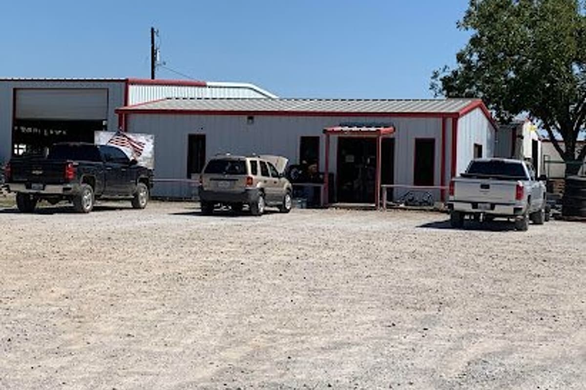 Central Texas Recyclers: Red-trimmed metal shop building with open entrance and pickup trucks and an SUV parked on a gravel lot