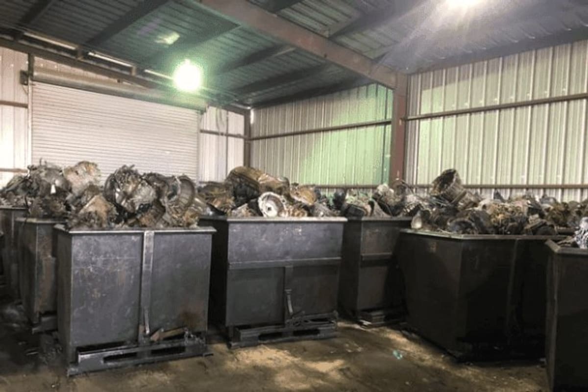 J P Transmission Recycling: Large metal bins filled with used transmissions and metal parts inside a covered storage area