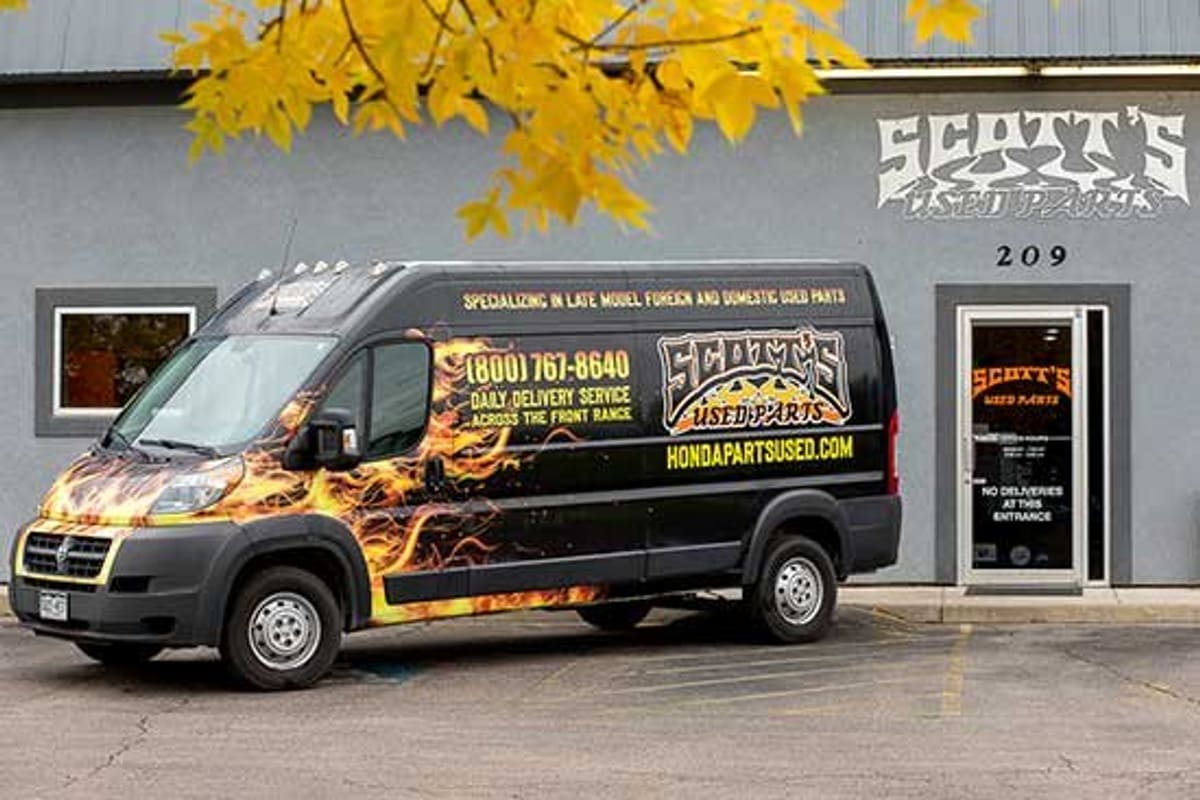 Scott's Used Parts: Gray shop building with address 209 and glass entrance door, a flame-painted delivery van parked out front