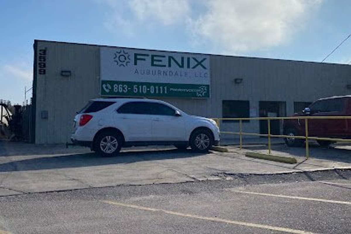 Fenix Parts - Auburndale: Single-story metal industrial building with a large wall sign and phone number, a white SUV parked in front