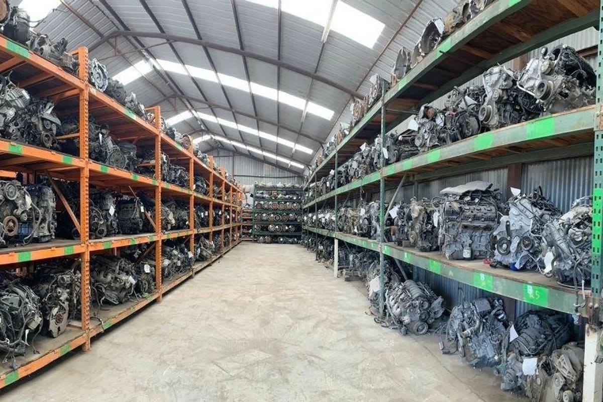 E & D Complete Auto Parts: Panoramic view inside a warehouse with shelves of used car engines lined up along both sides of a concrete aisle