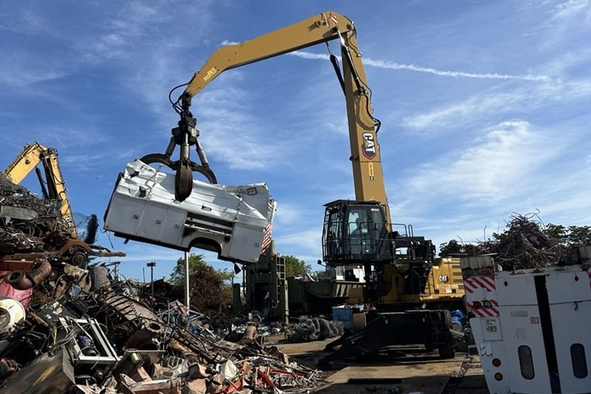 SA Recycling - Pompano Beach: Yellow material handler crane lifting scrap metal above piles of salvage in an open recycling yard under a blue sky