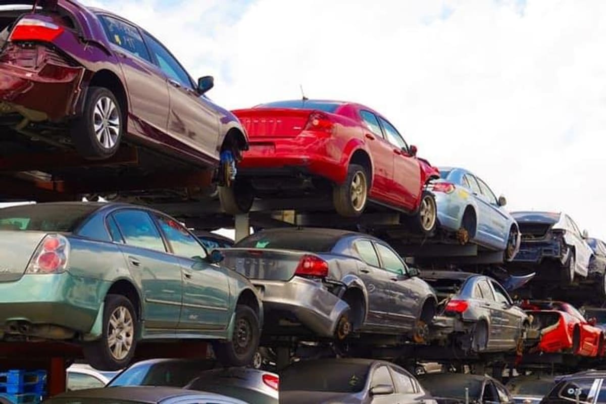 MR Used Auto Part: Stacked wrecked cars on racks in a salvage yard under a cloudy sky