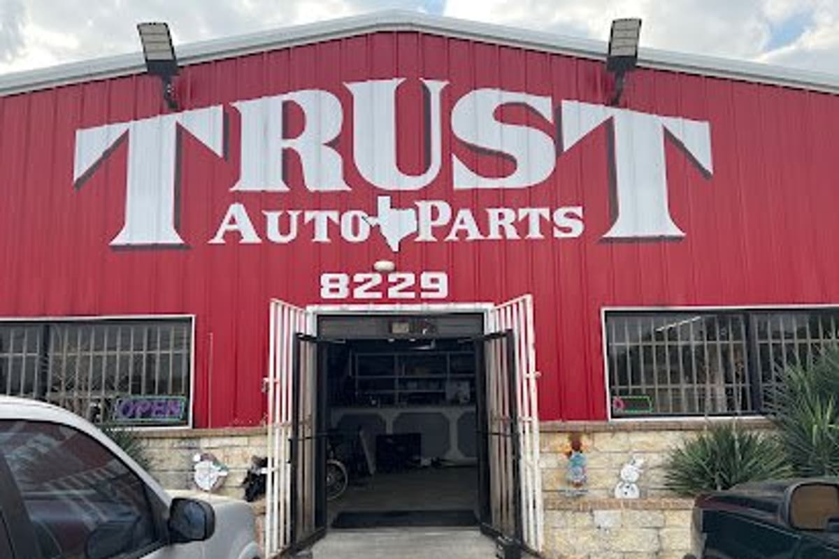 Trust Auto Parts: Red metal building with large white TRUST Auto Parts lettering, street number 8229 and open double doors