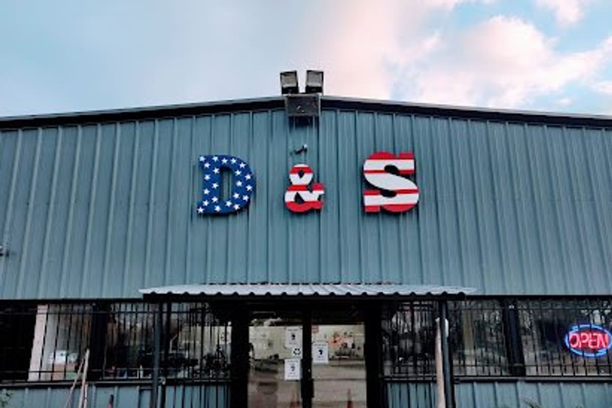 D&S Imports: Metal building with red, white and blue D & S letters above a gated entrance and a lit open sign