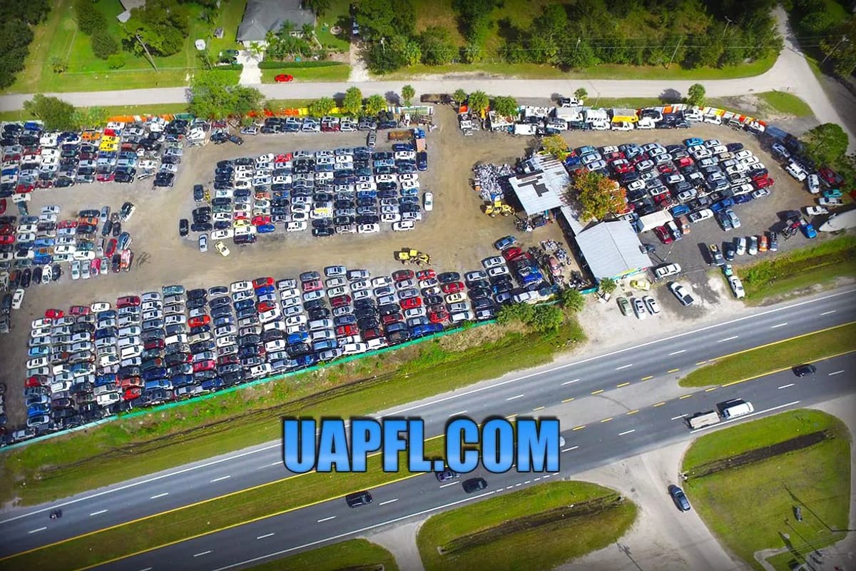 ABC Used Auto Parts: Aerial view of a large salvage yard with rows of cars beside a highway and small buildings on the lot