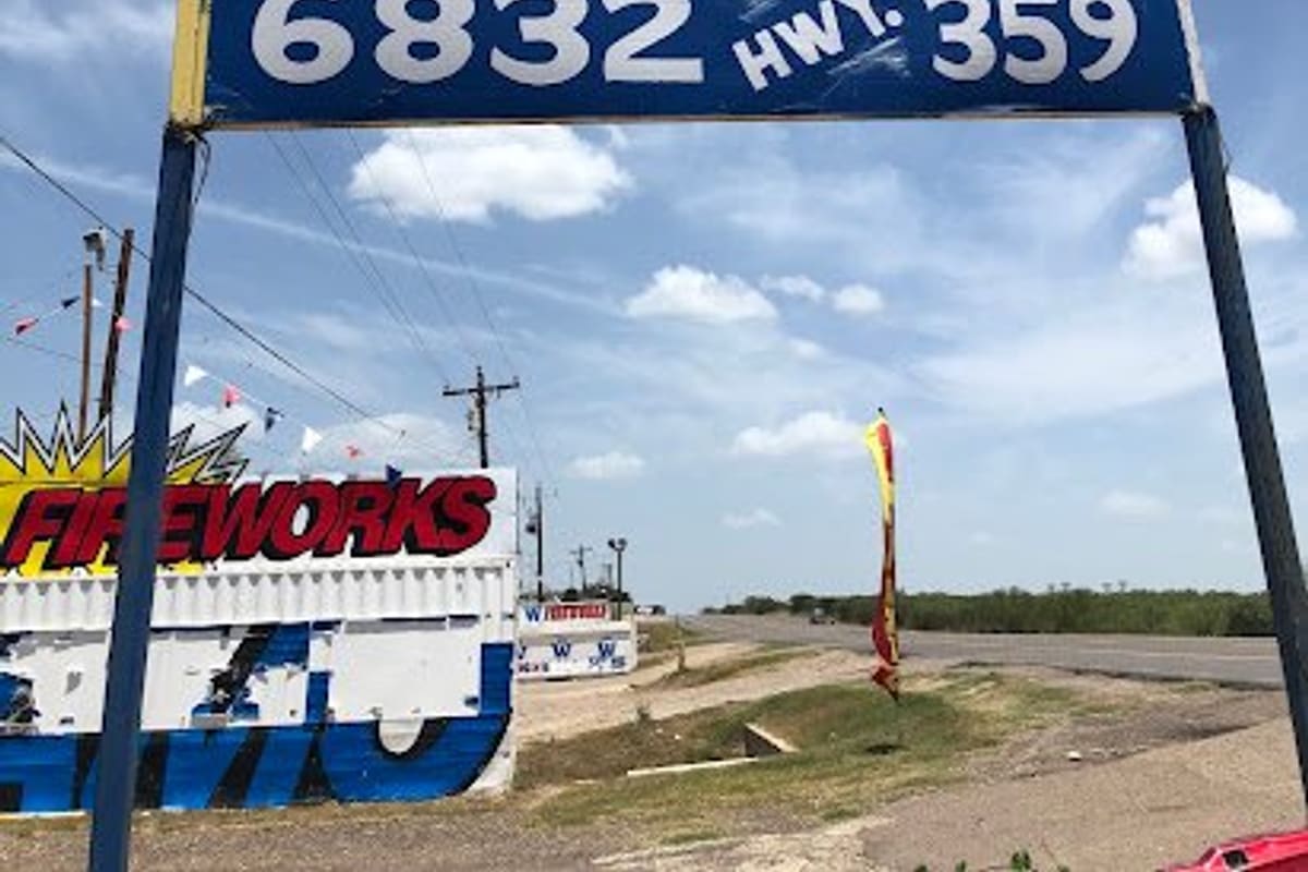 Hernandez Auto Parts & Auto Sales: Large blue roadside sign reading Hernandez Auto Parts, 6832 Hwy. 359, with a highway and fireworks stand nearby