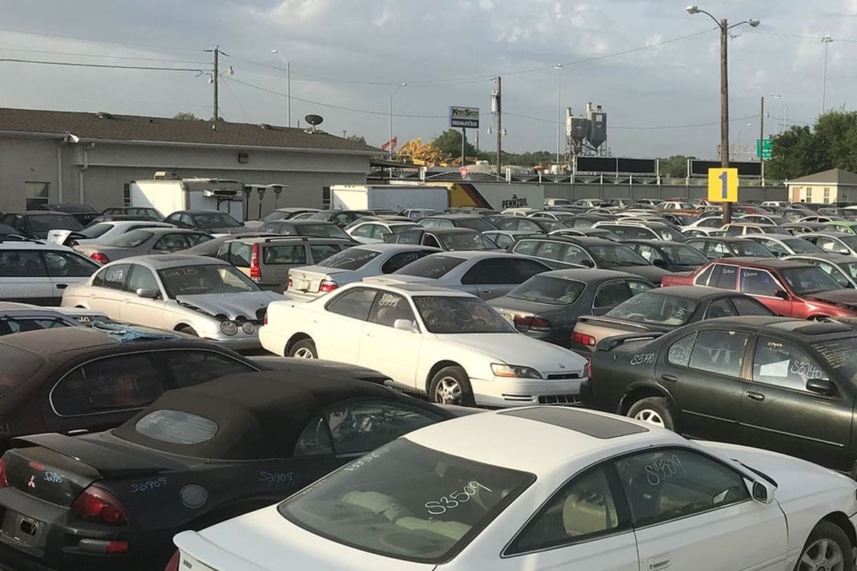 Garland Auto Recyclers and Auto Parts: Wide view of rows of used cars parked in a gravel salvage yard under a partly cloudy sky