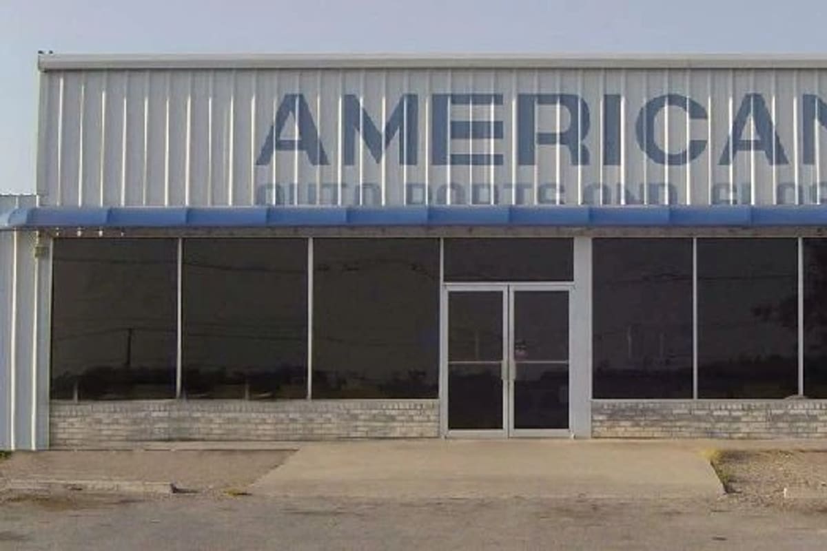 American Auto Parts: Metal storefront building with a blue awning, large windows, glass double doors and a large sign on the upper wall