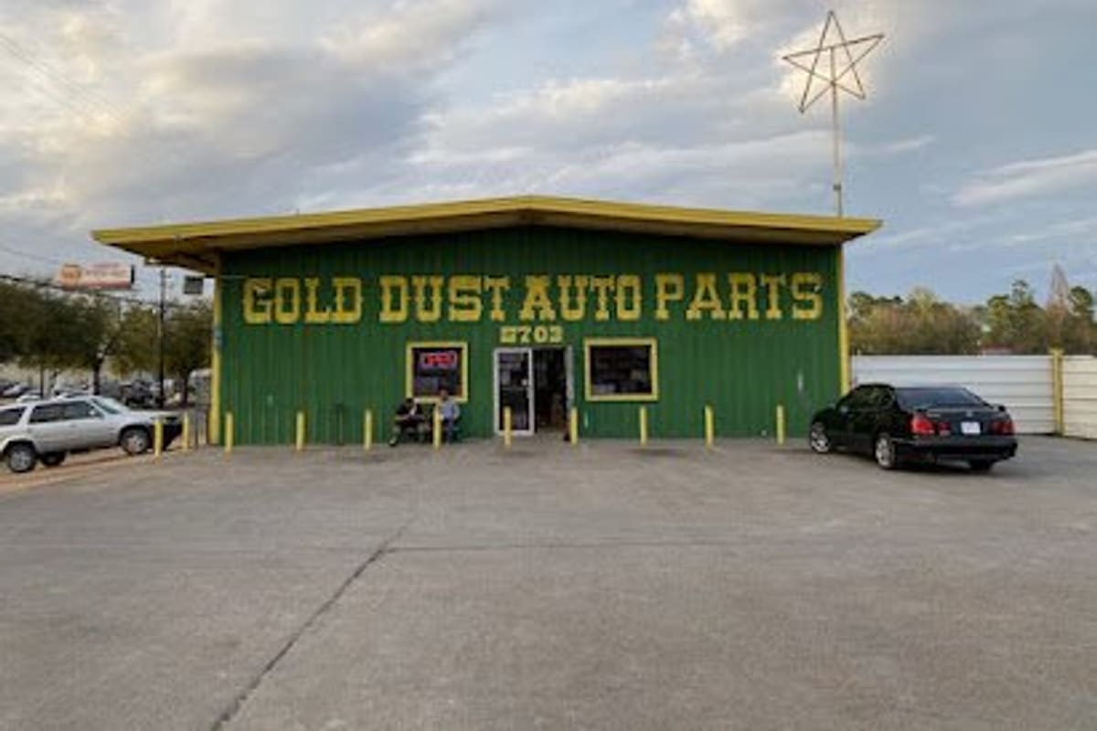 Auto Parts Express: Green auto parts store with yellow lettering and open door, parked cars and yellow bollards on a paved lot
