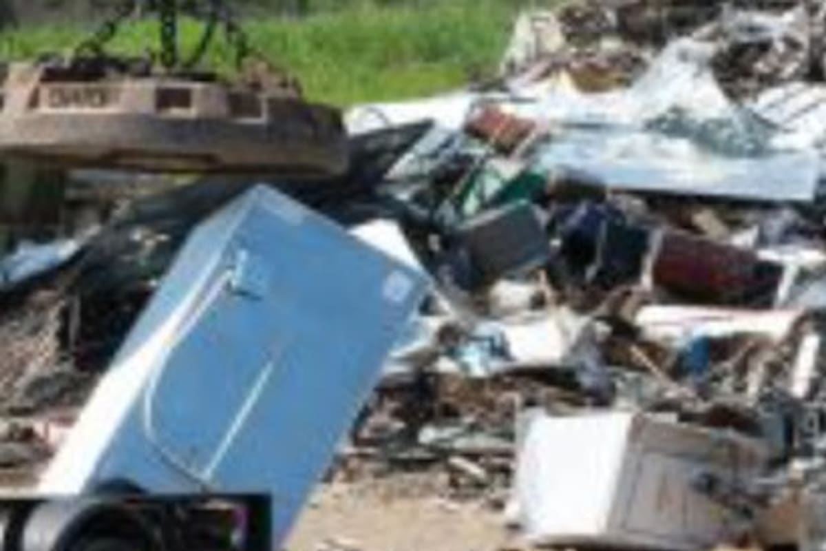 Creson's Auto Sales & Recycling: Pile of scrap appliances and debris on a dirt lot, with a refrigerator loaded on a trailer in the foreground