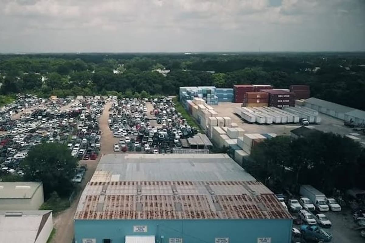 Lakeland Auto Salvage: Aerial view of a large salvage yard with rows of cars, shipping containers and a blue warehouse building