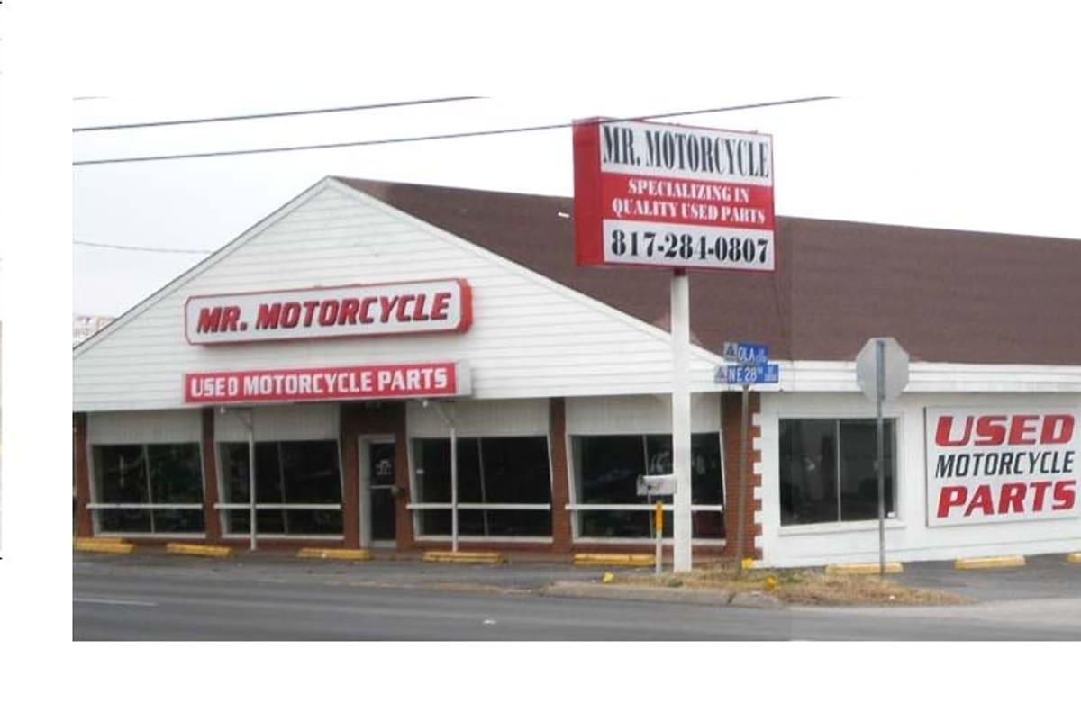 MR Motorcycle: White single-story storefront with a tall roadside sign and red signs reading used motorcycle parts