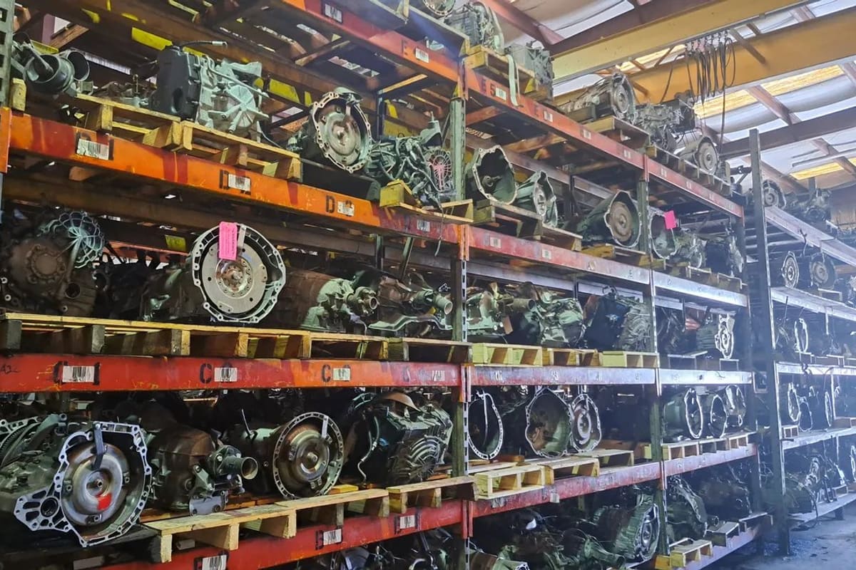 Ace AA Used Auto Parts: Warehouse shelving racks stacked with used transmissions and engines on pallets